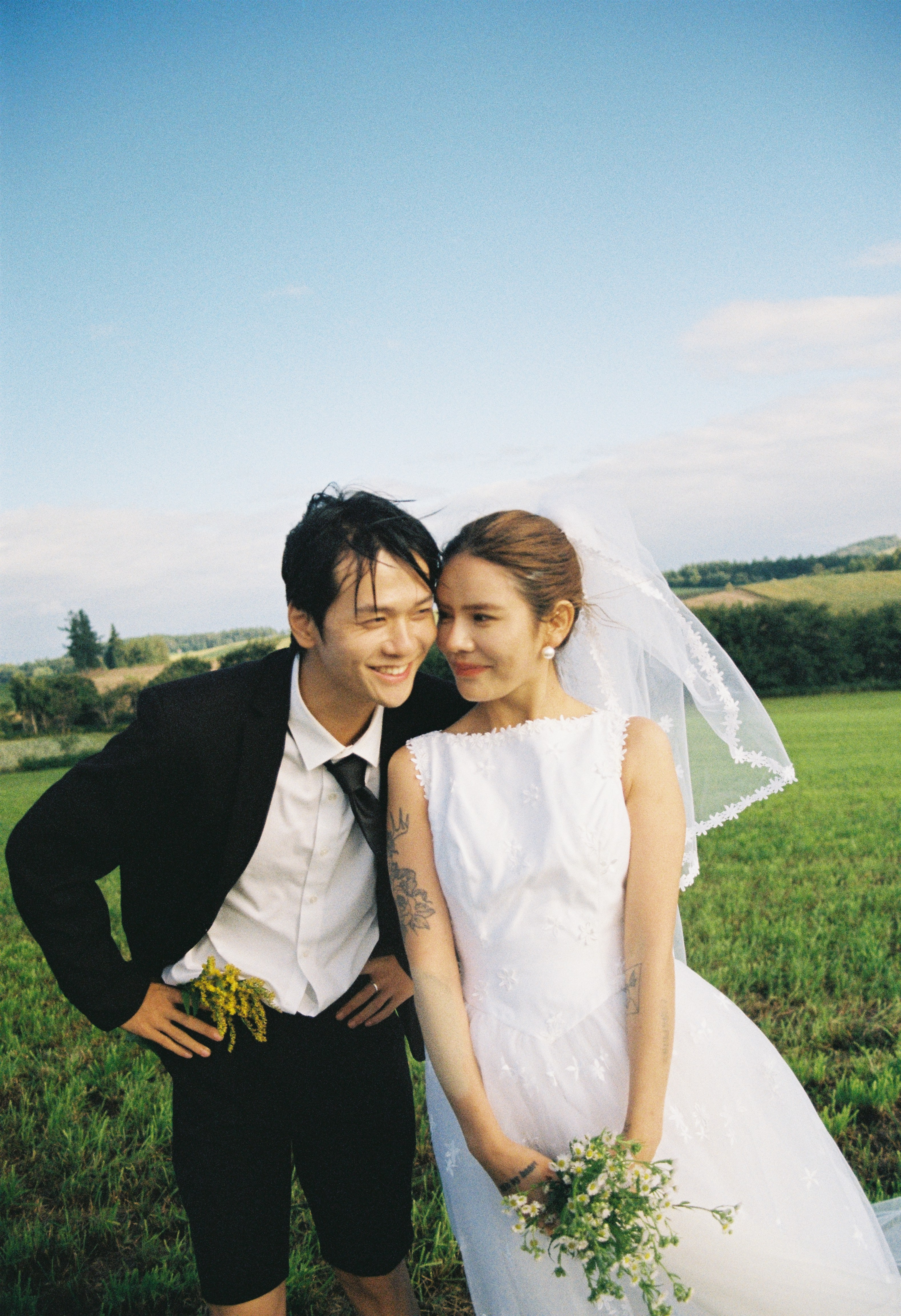 北海道草地上新娘与新郎相靠的婚纱照