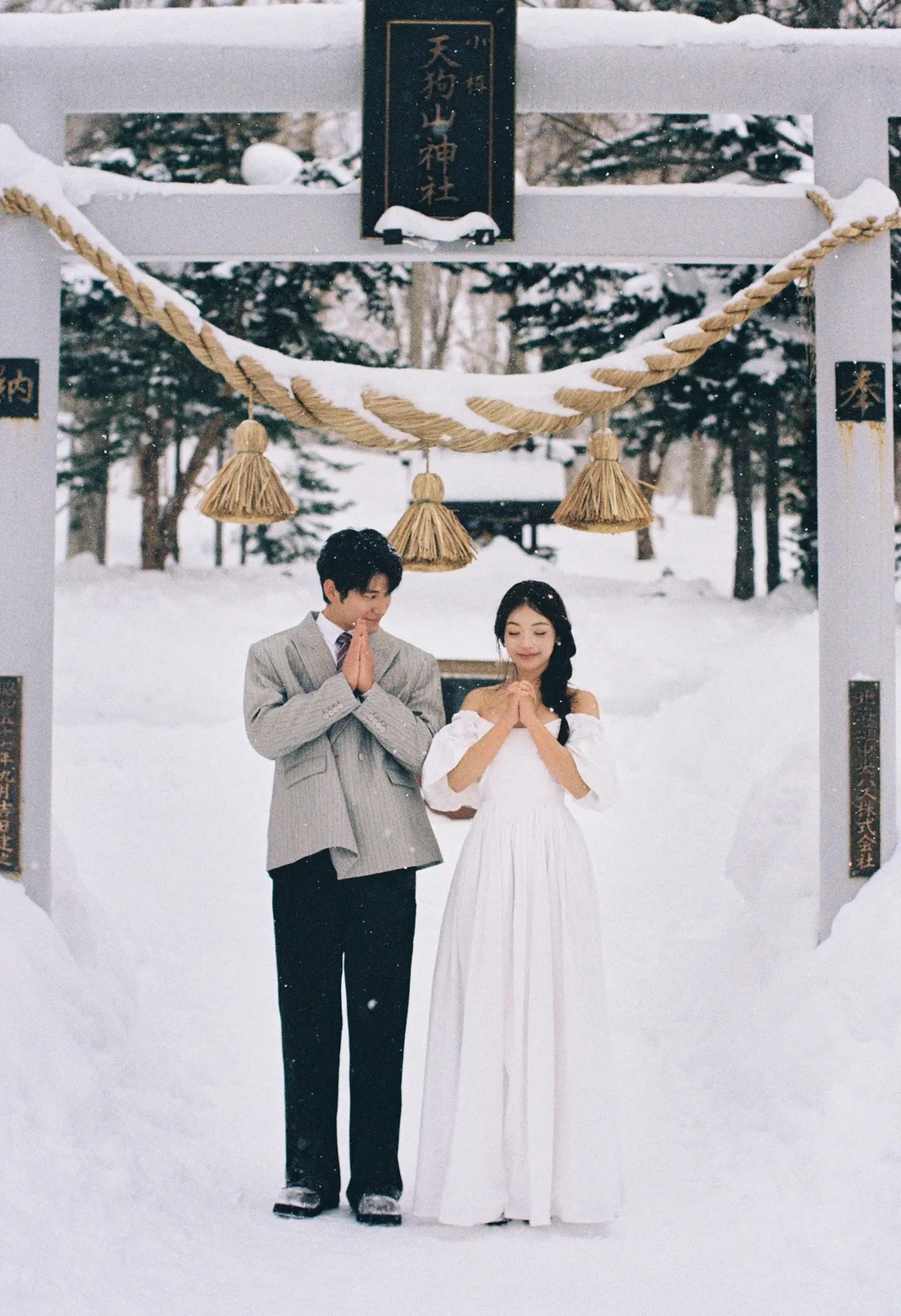 北海道雪地神社鸟居下并肩祈愿的情侣