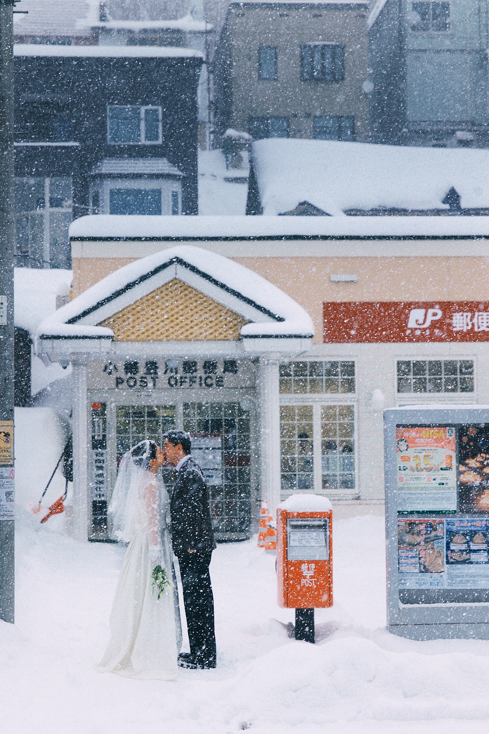 小樽积雪的街道旁，两个人在店门前相拥
