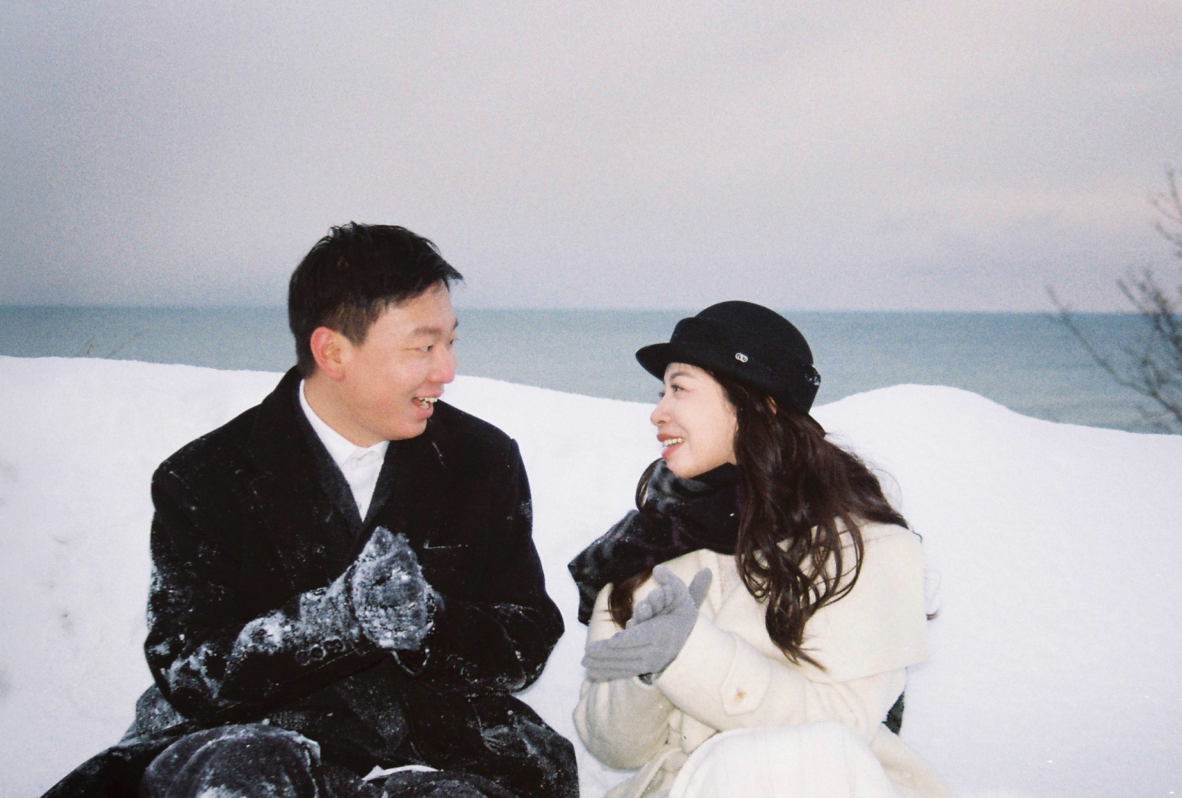 雪地海边，穿冬装的两个人相对微笑