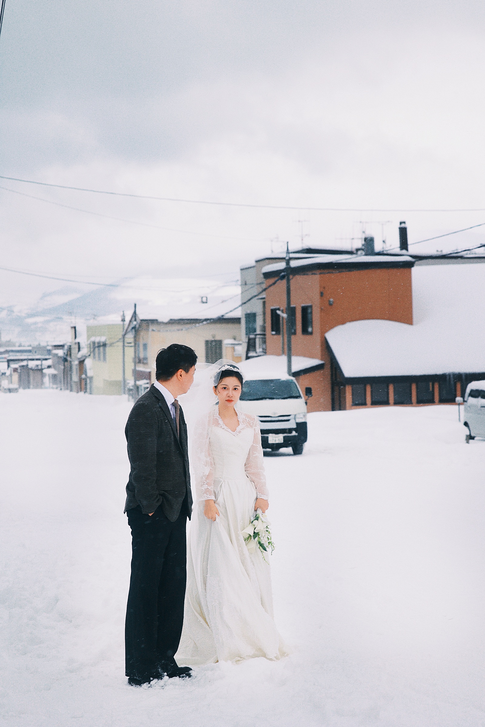 覆雪街道旁，两个人牵手面对面站立