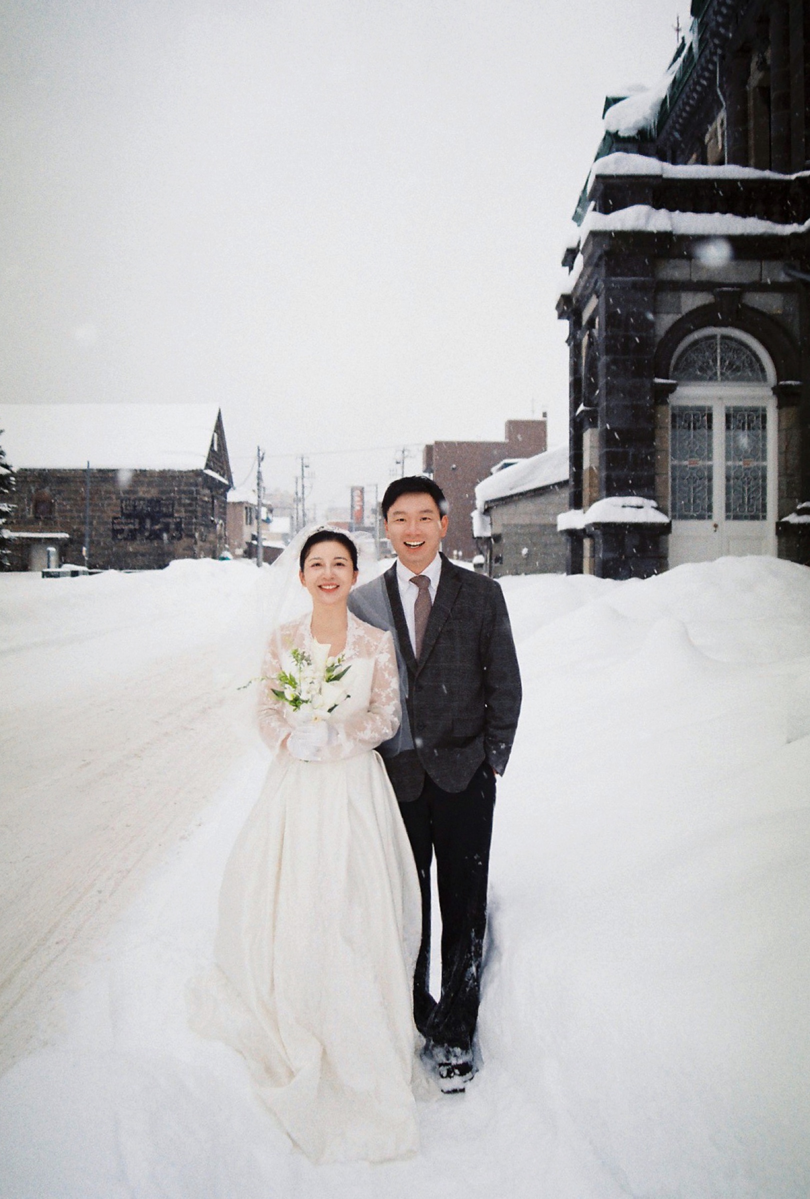 石造建筑旁，两个人在雪路上并肩站立