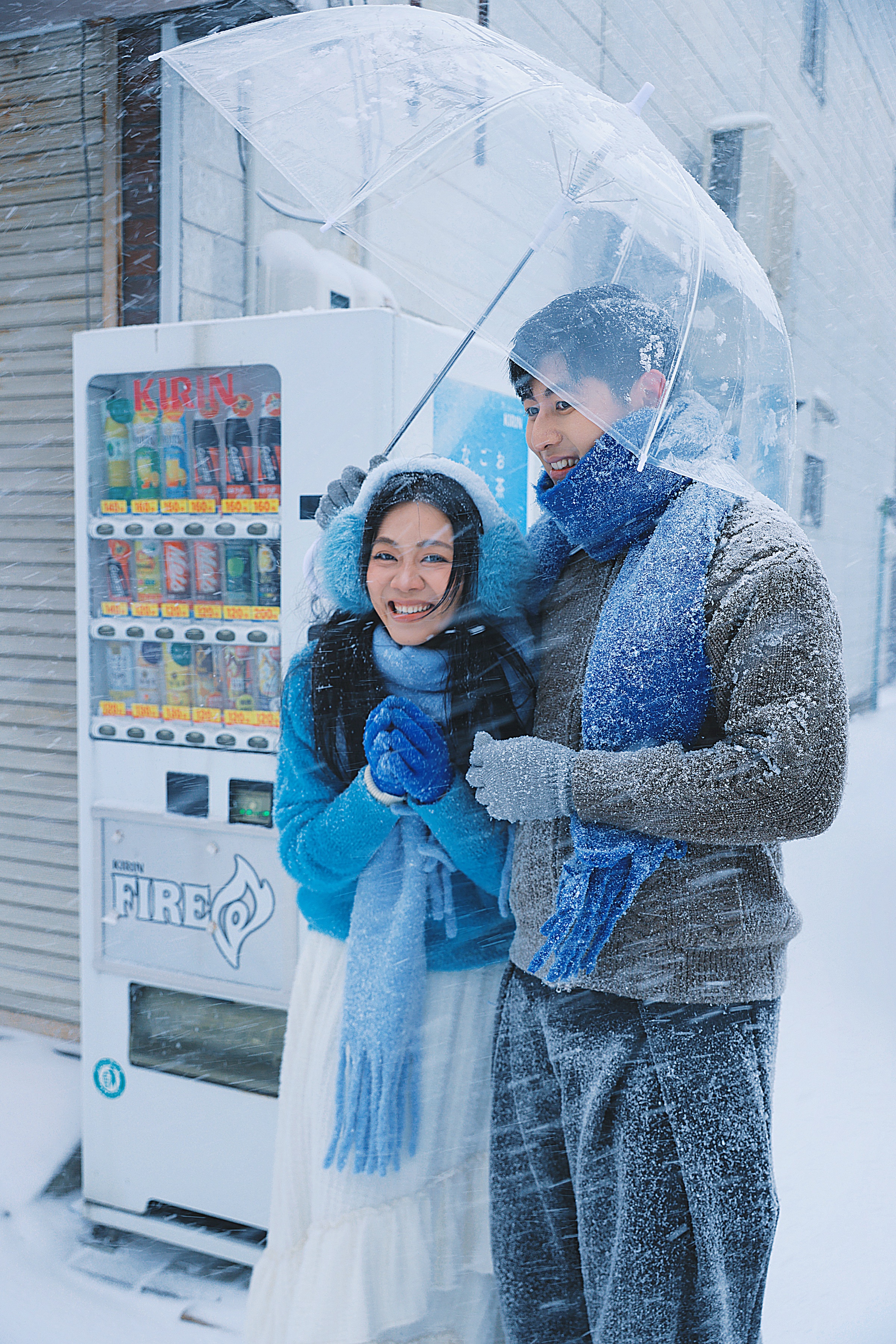 落雪的街边，两个人撑着透明伞依偎在一起