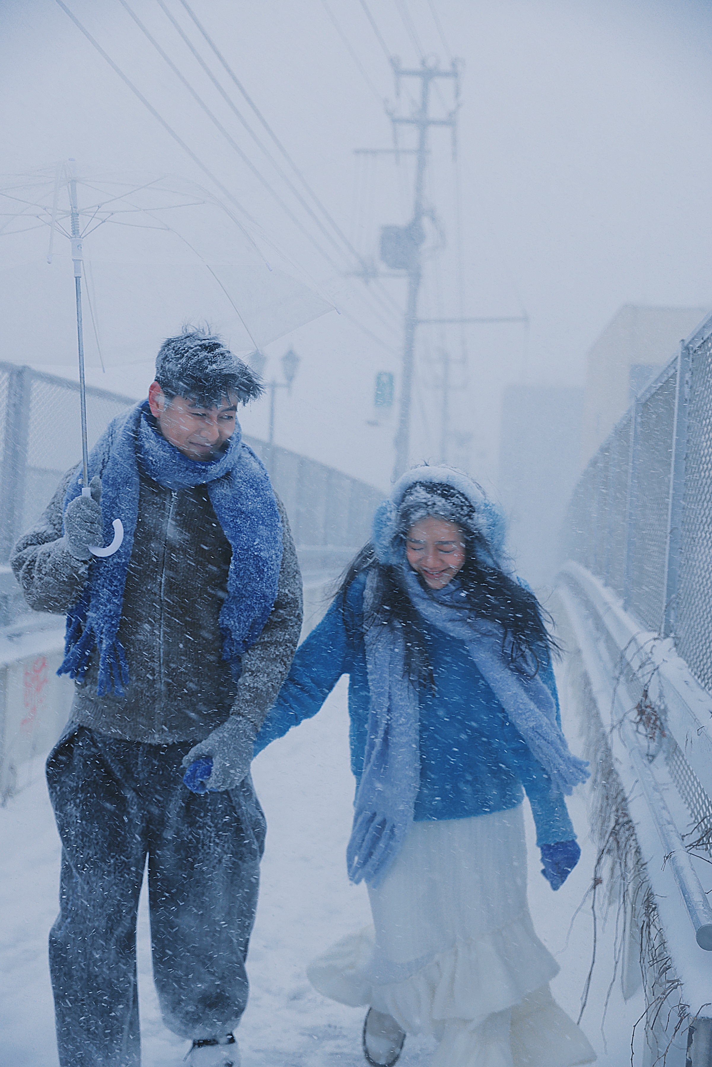 雪中街道上，两个人牵手向前走