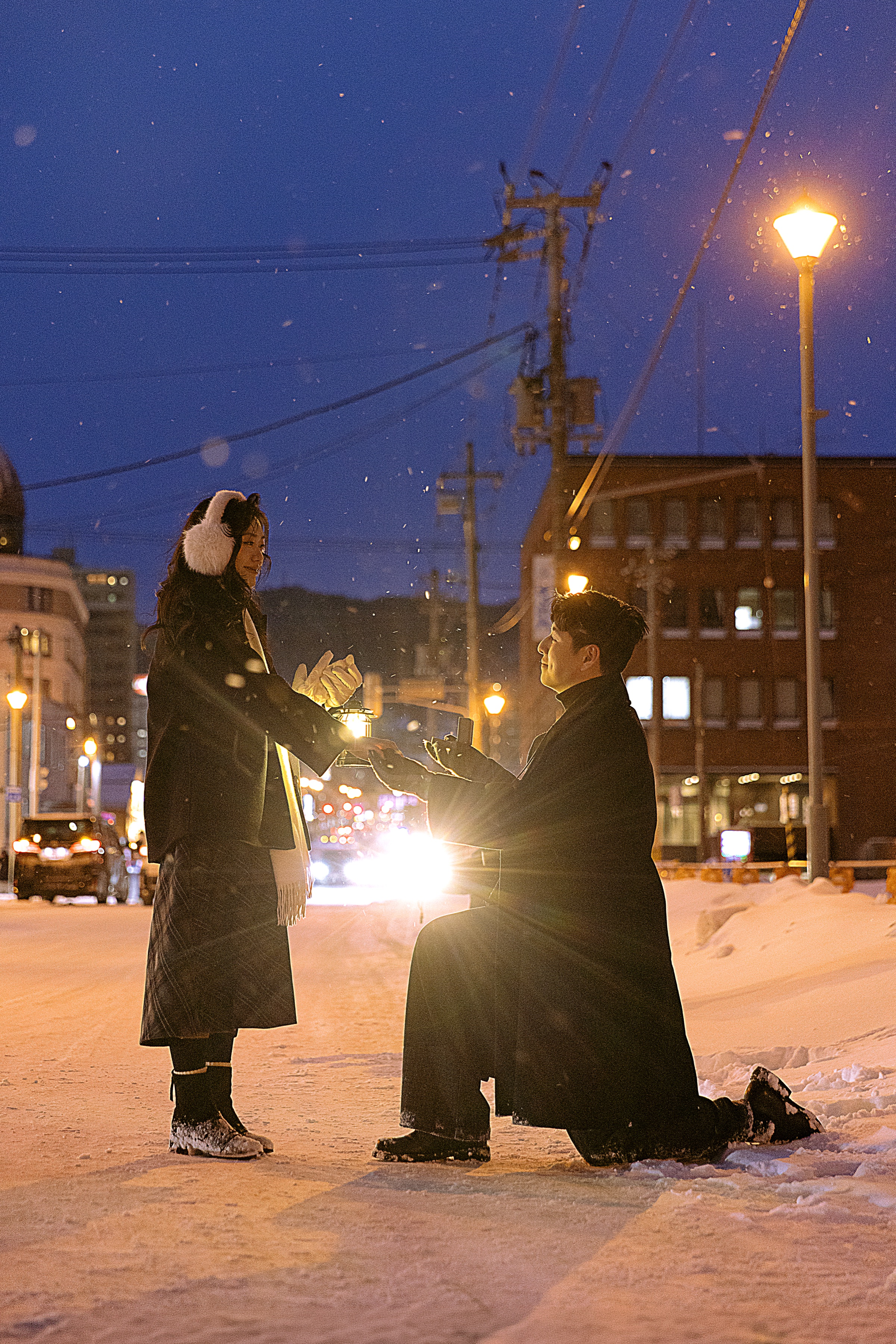 路灯下，两个人穿深色外套面对面站在雪地里