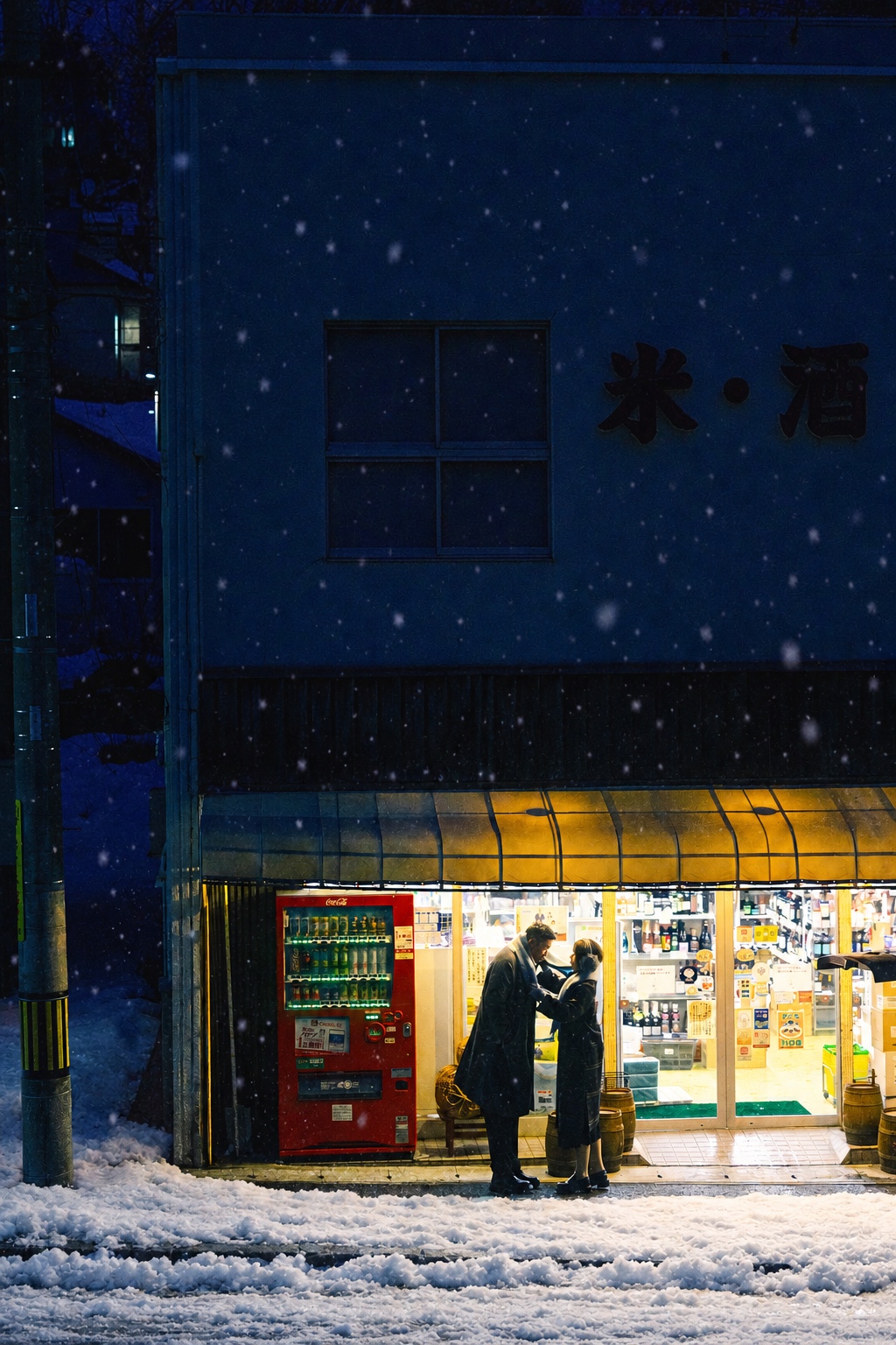 深蓝夜色中，两个人站在明亮的小店门前