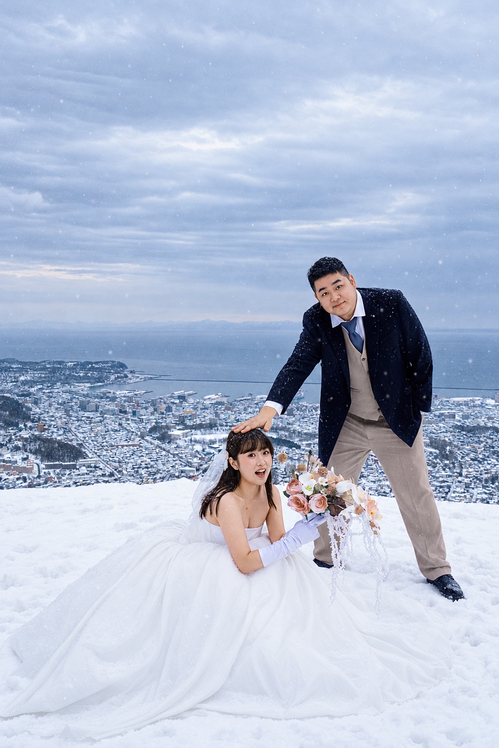 雪坡上，新娘坐在裙摆间，新郎站在身旁