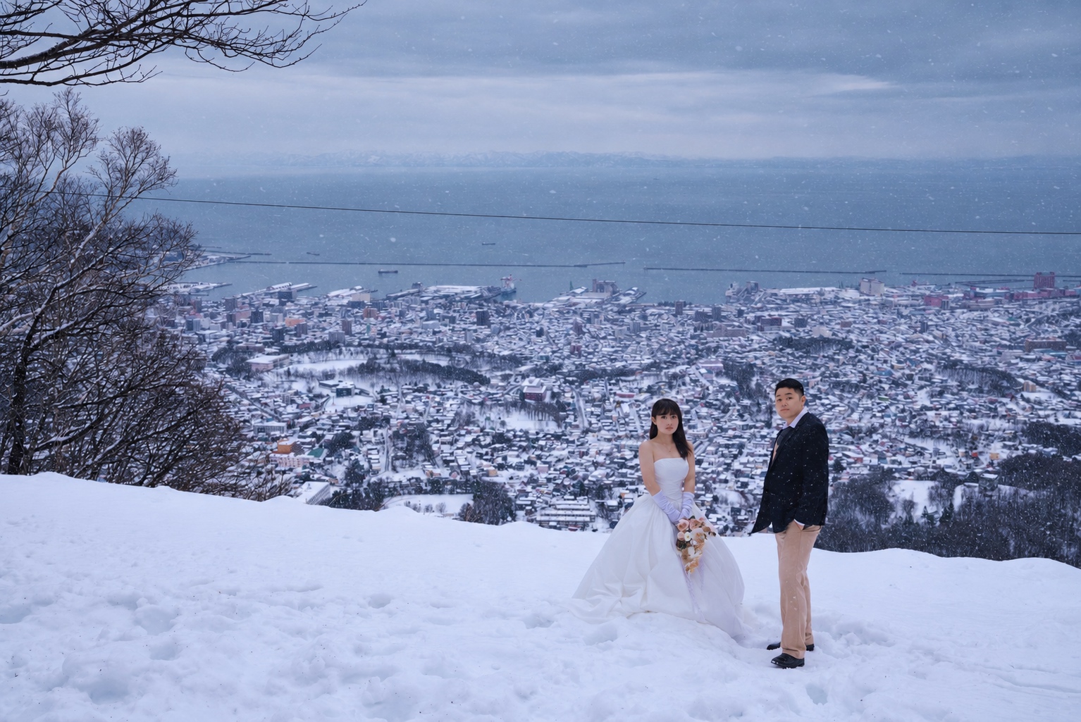 城市与海的远景前，两个人牵手站在雪坡上