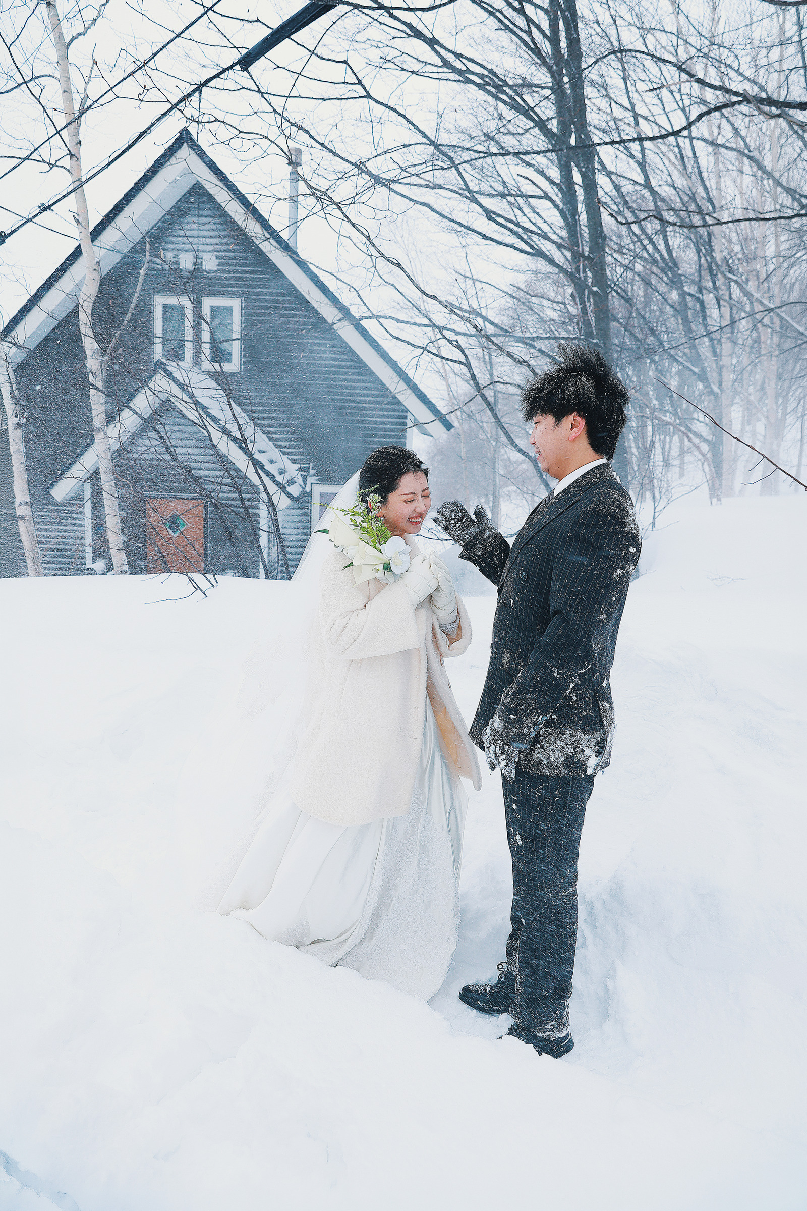 小樽木屋前牵手站在雪中的新人