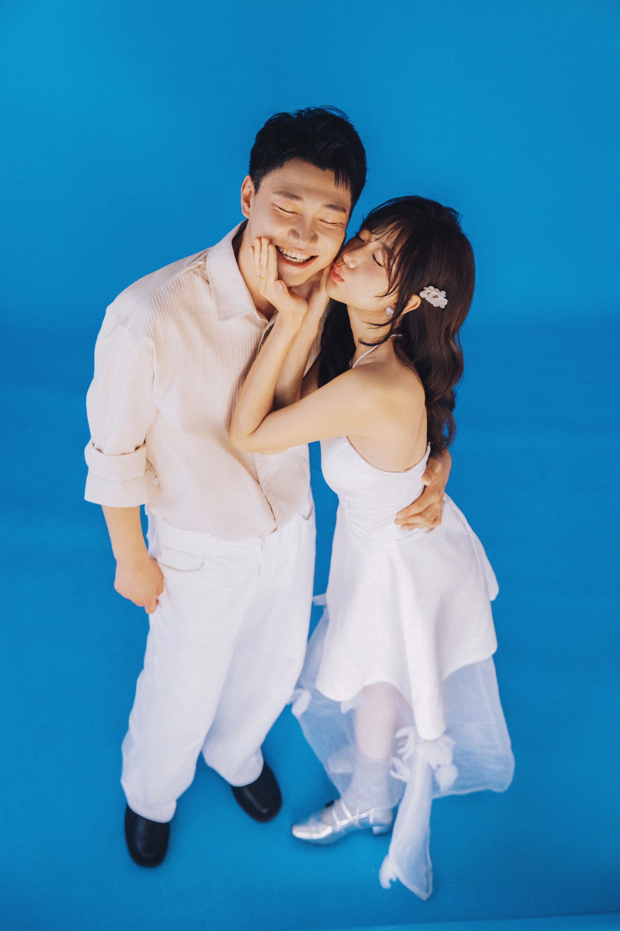 青い背景の前で頬にキスをするふたり
