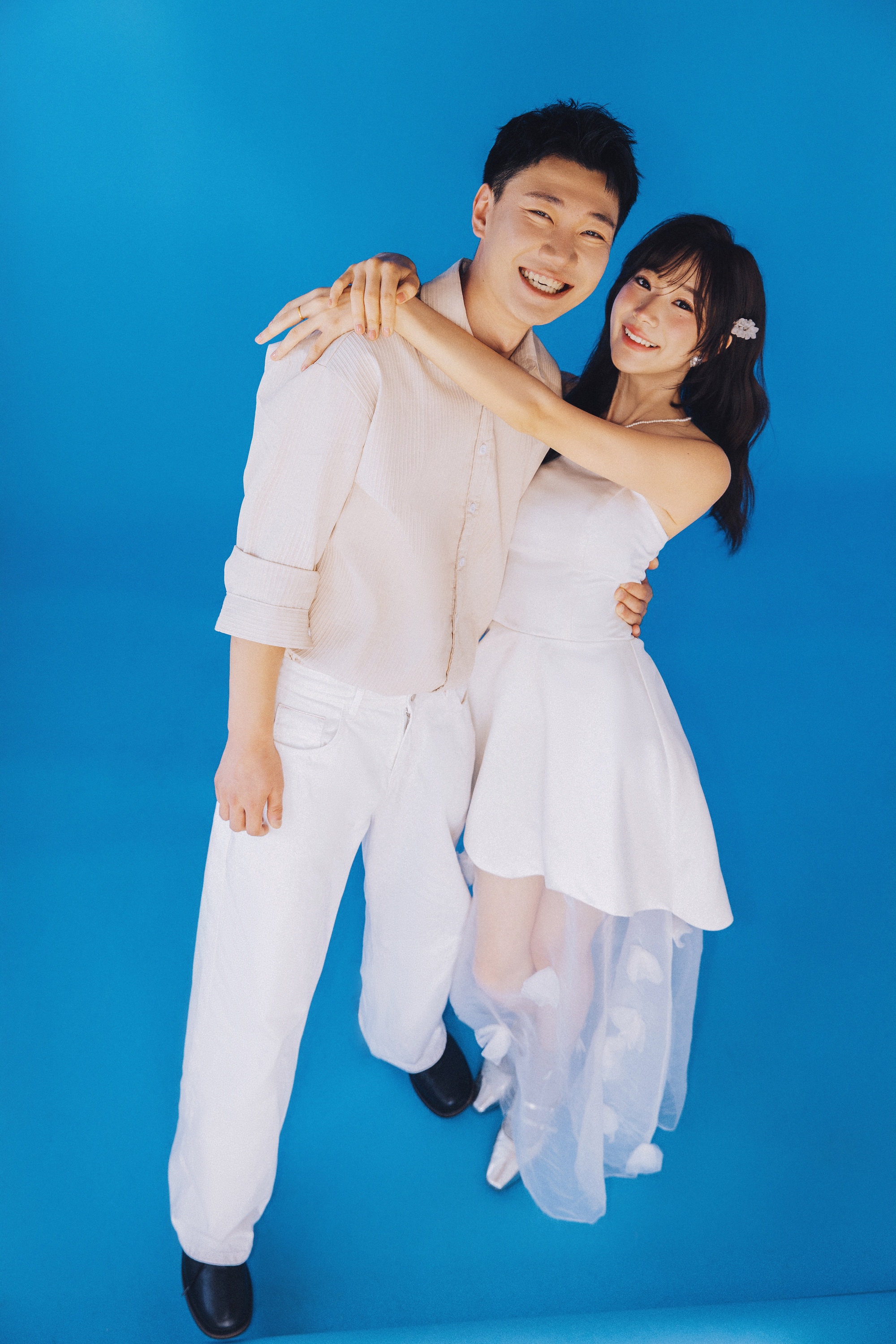青い背景の前で笑いながら抱き合うふたり