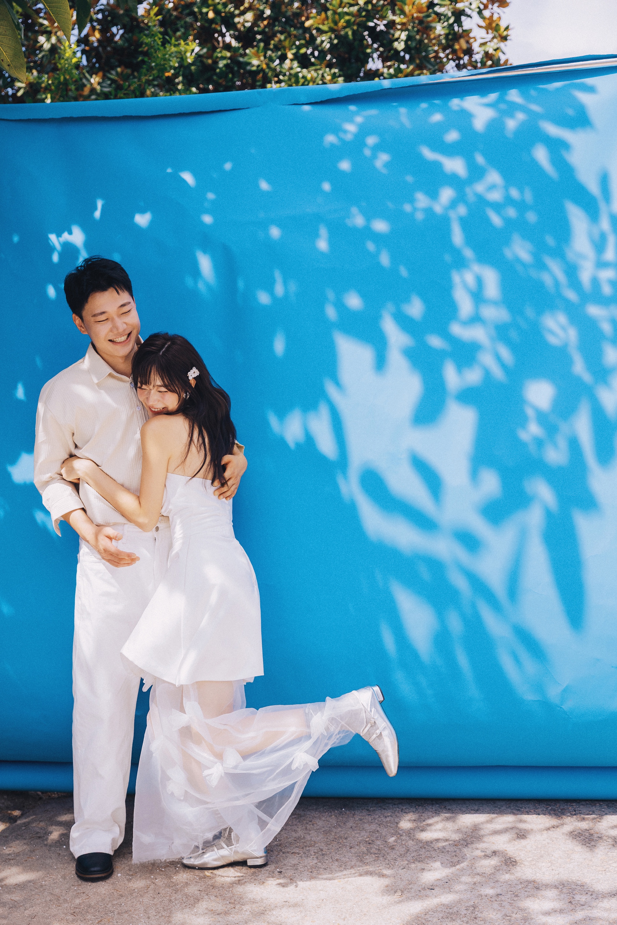 葉の影と青い背景の前で抱き合うふたり